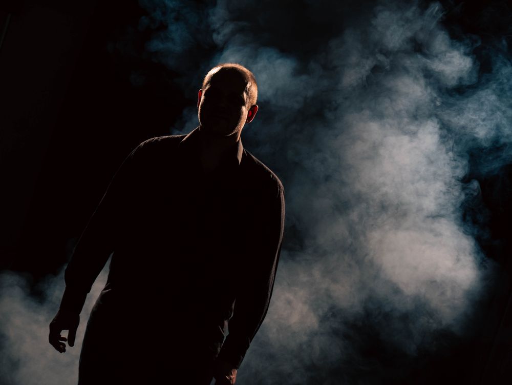 Ein Foto in einem Studio. Nebel im Hintergrund und eine Person im Vordergrund wo fast nur die Silhouette erkennbar ist.