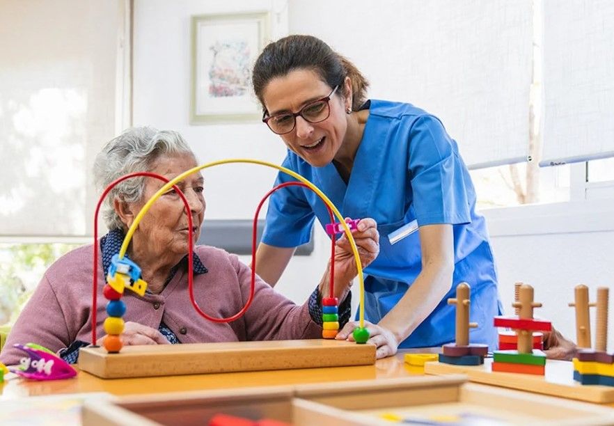 A healthcare worker with a dementia patient playing with a wooden toy.