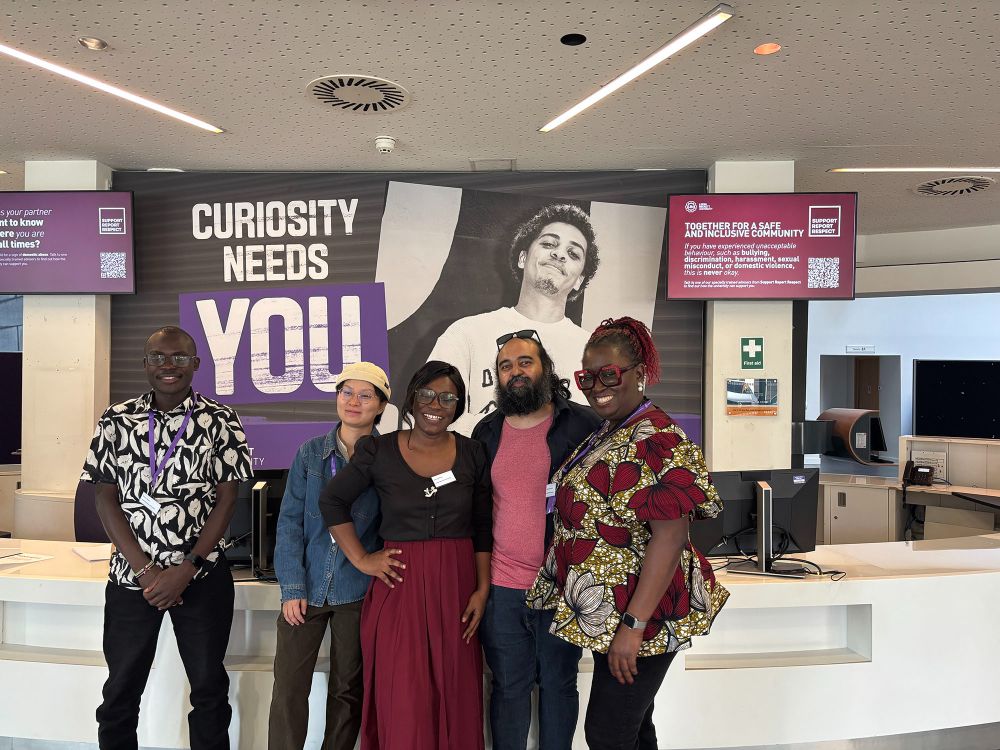 Misan with 4 members of the conference organising committee in the Rose Bowl reception, with an LBU banner behind them which reads 'Curiosity Needs You'