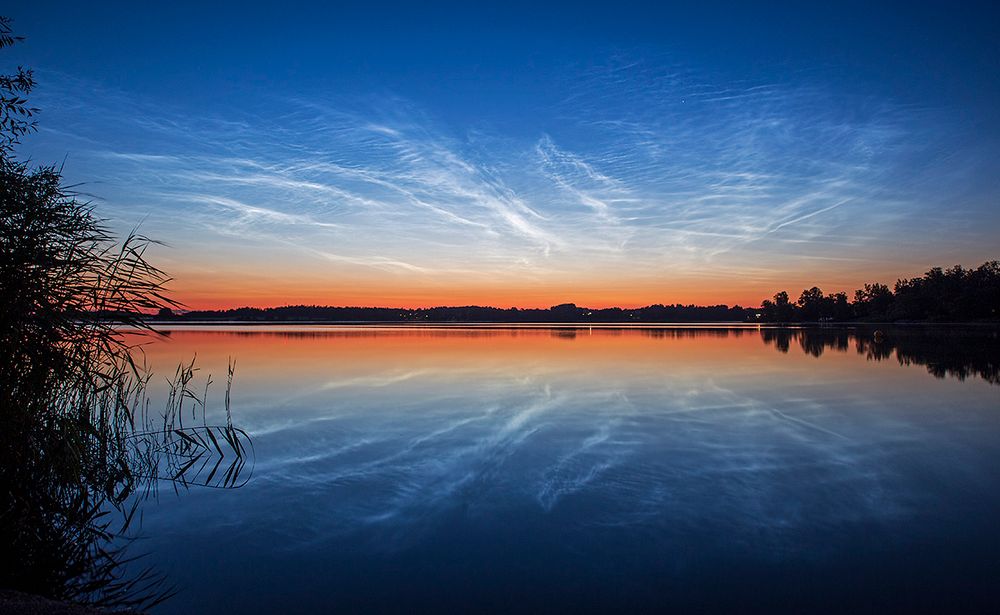 Transfusing sunlight as the sky grew darker, this exceptional display of noctilucent clouds was captured on July 10, reflected in the calm waters of Vallentuna Lake near Stockholm, Sweden. From the edge of space, about 80 kilometers above Earth's surface, the icy clouds themselves still reflect sunlight, even though the Sun is below the horizon as seen from the ground. Usually spotted at high latitudes in summer months, the night shining clouds have made a strong showing so far during the short northern summer nights. Also known as polar mesopheric clouds they are understood to form as water vapor driven into the cold upper atmosphere condenses on the fine dust particles supplied by disintegrating meteors or volcanic ash.