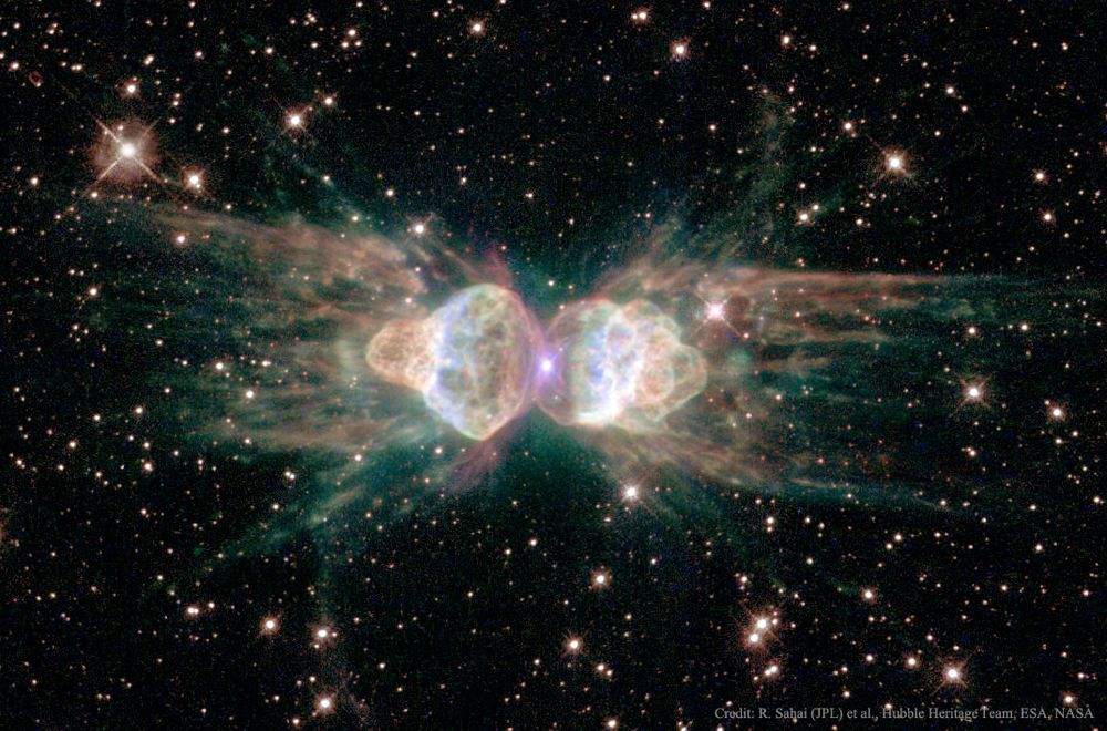 A dark starfield appears around an unusually shaped nebula. The nebula has two main lobes on the left and the right and may seem to resemble an ant. Please see the explanation for more detailed information.