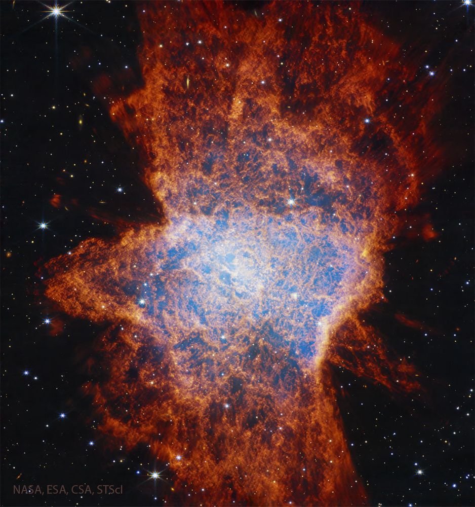 A starfield is shown dominated by a complex nebula shown with many red filaments and with a light glow in a region near the center. Please see the explanation for more detailed information.