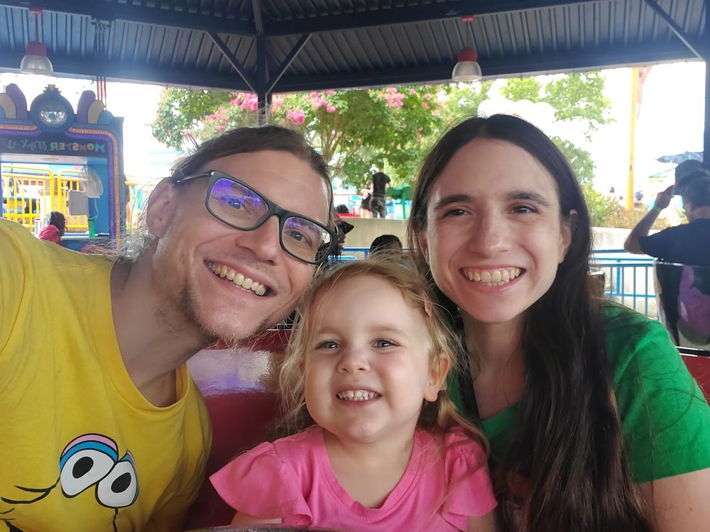 Picture of the fam: me in a Big Bird shirt, kiddo in a pink shirt, and my wife in a green shirt.