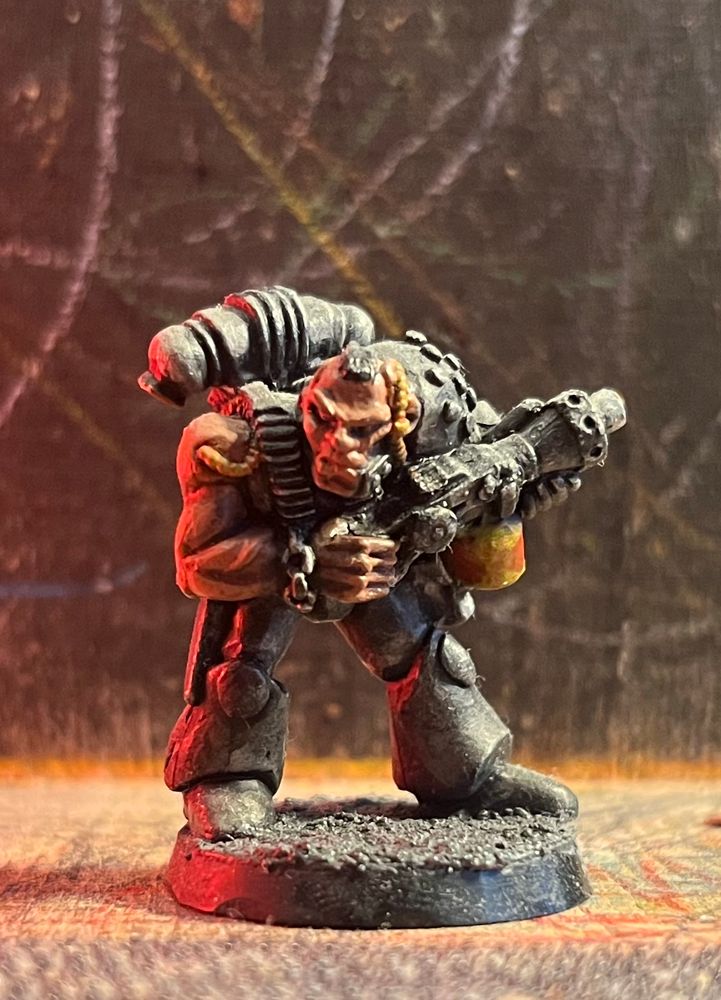 Oldschool wh40k miniature in strong red light coming from left. Metal cast space marine with mohawk hairstyle and flamer.