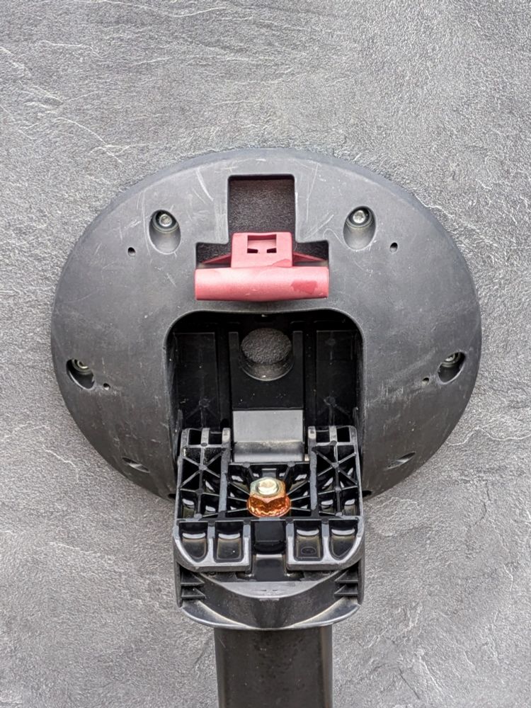 Runder Montage-Eingang einer hochgestellten Halterung mit geöffneter Klappe. Die beiden Schrauben oben schauen, der rote Hebel riecht und aus der dunklen Öffnung ruft das "Gesicht".