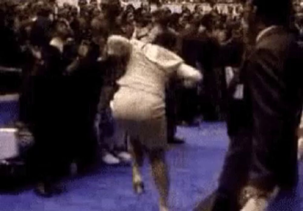 a woman in a white dress is dancing in front of a crowd .