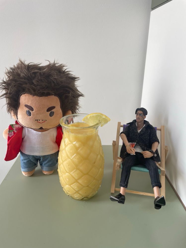 Ichiban Kasuga plushie and Majima Goro action figure with a huge pineapple juice
