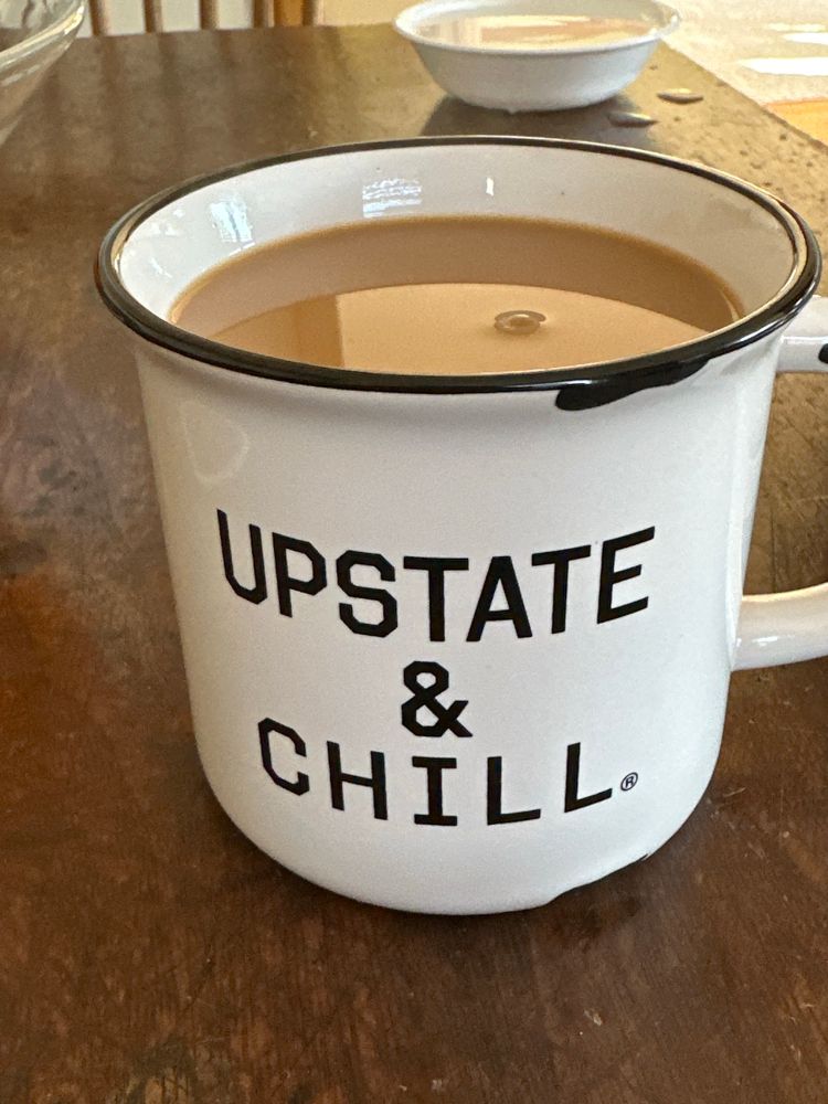 White coffee mug with black rim and the words “Upstate and chill”