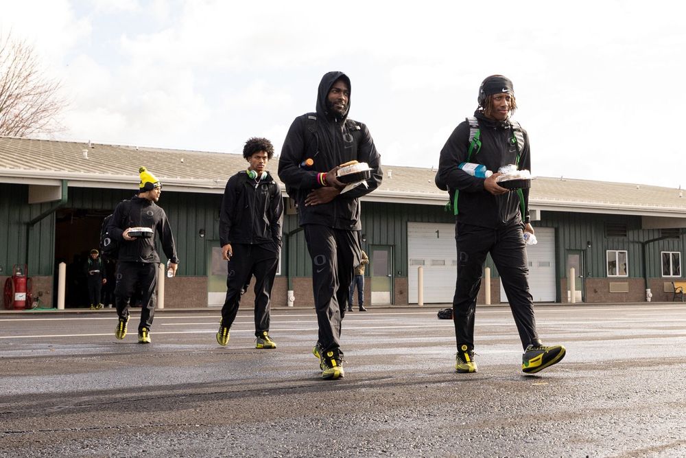 Oregon ducks football players walking with food trays in hand and headphones around their necks