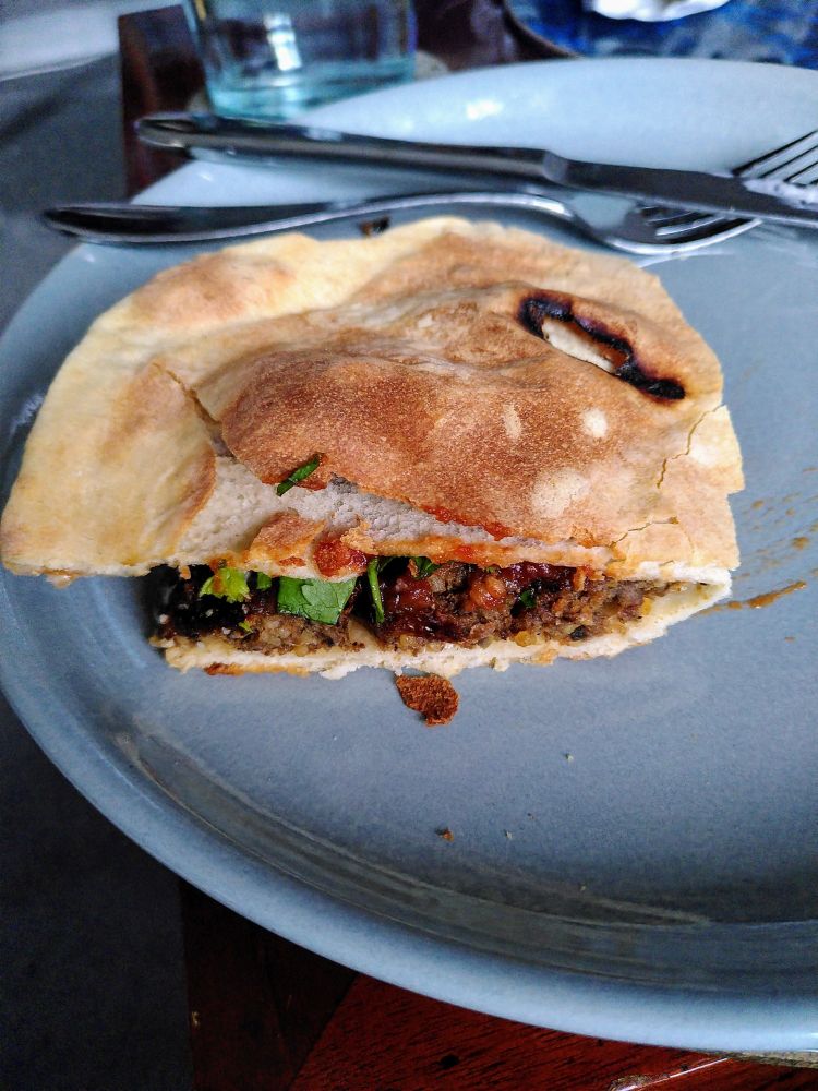 Vegan sausages, tomato and chilli jam, coriander, cream cheese, in a folded naan bread from Dishoom