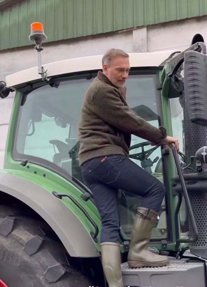 Ein Mann steht auf der rechten Seite eines Traktors und kommt nicht rein. Bekanntlich kommt man dies nur auf der linken Seite.