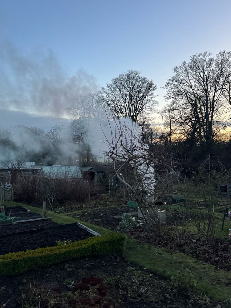 Smoky fire in the allotment with sunset in the background. 