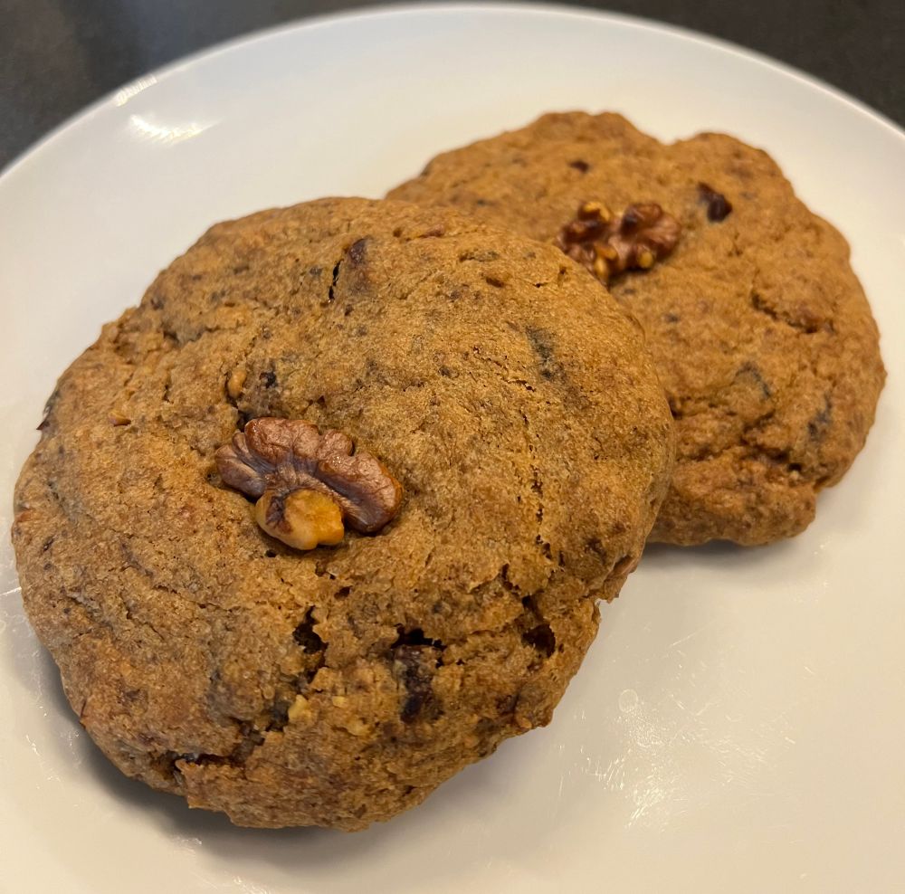Two delicious-looking date & walnut cookies on a white plate