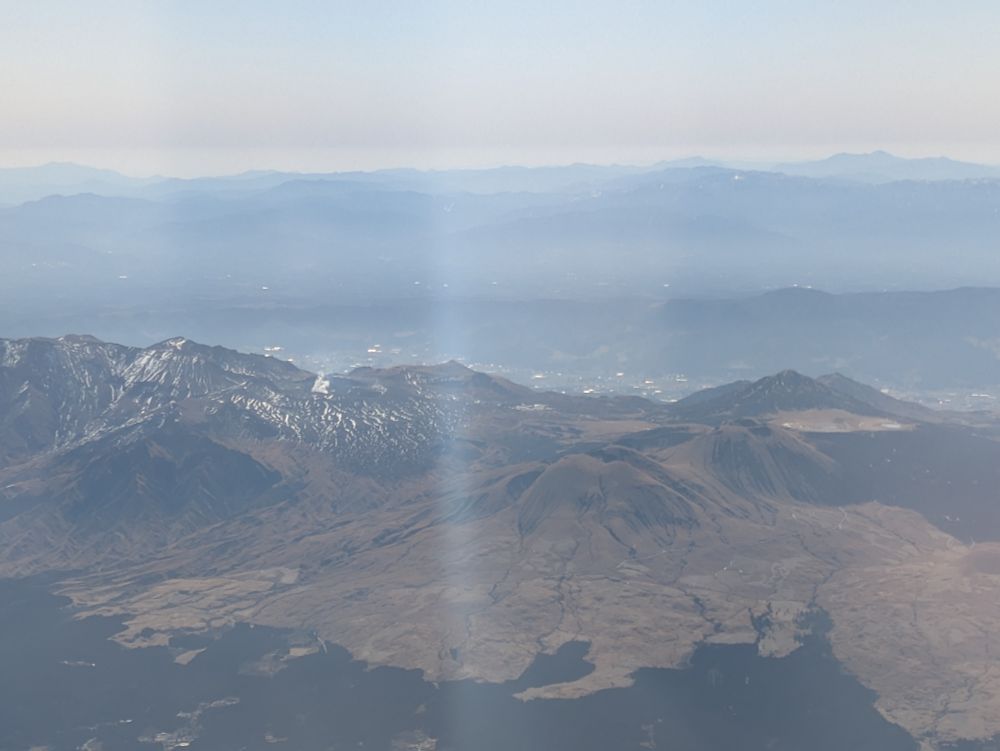 阿蘇山火口とわずかにあがる煙、草千里を飛行機から撮った写真