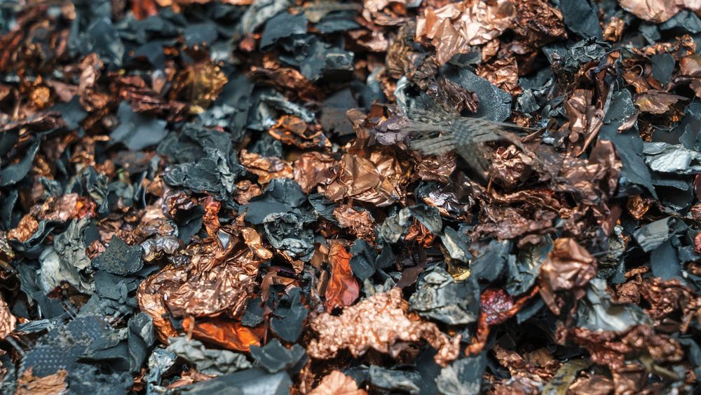 Flakes of black and gold metal in a pile forming black mass, a base to make new lithium batteries for cars.