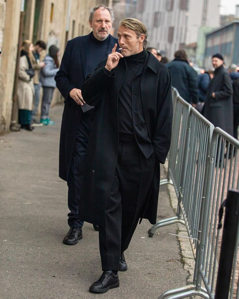 Mads Mikkelsen smoking and walking in all black during fashion week
