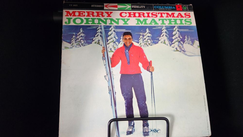 Johnny Mathis Merry Christmas LP album cover featuring Johnny with skis in the snow.