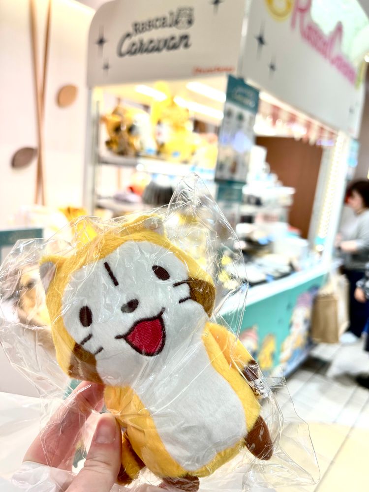 picture of a rascal plushie in front of the rascal caravan pop up store in tokyo stations character street
