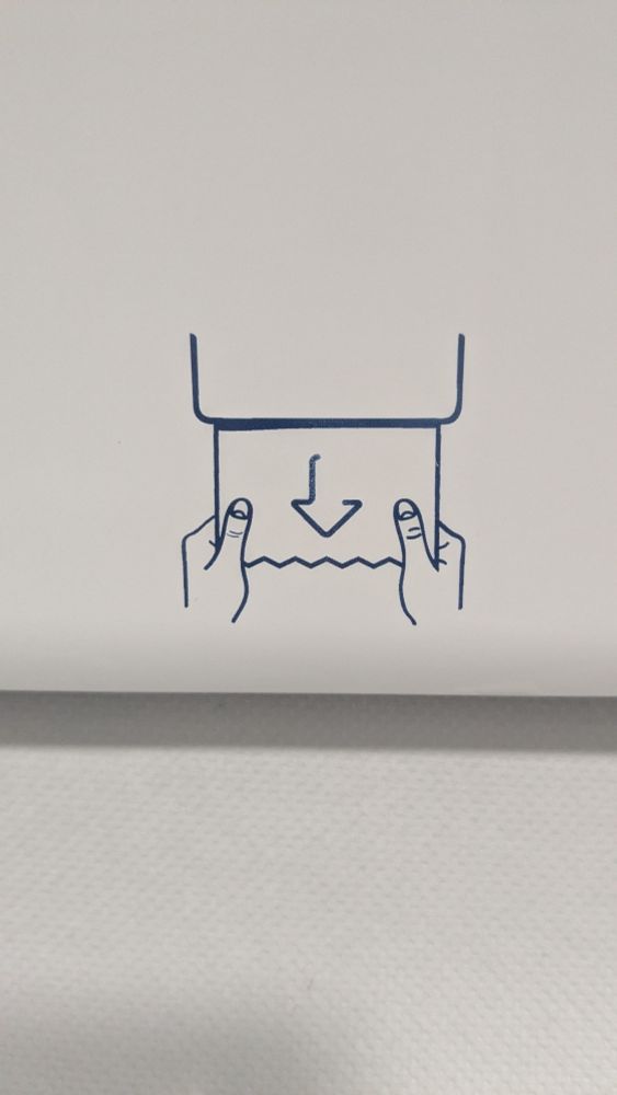 Schema showing how to pull some wiping paper from a dispenser. The arrow within the sheet of paper looks like a nose, which makes the whole scheme look like a face whose eyes would be masked by a hat (the bottom of the dispenser case)
