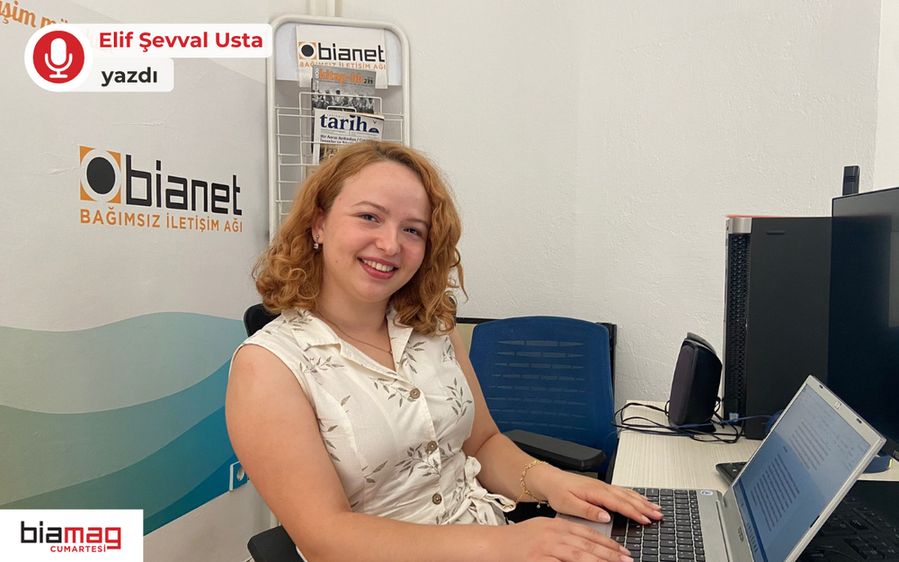 Görselde, bir ofis ortamında masasında dizüstü bilgisayar ile çalışan genç bir kadın gülümsüyor. Arka planda bianet logosu, kitaplık ve dergiler yer alıyor. Sol üstte "Elif Şevval Usta yazdı" ifadesi, sol altta ise "biamag cumartesi" logosu bulunuyor.