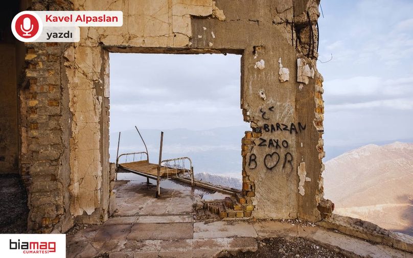 Görselde, harabe haline gelmiş bir yapının içinden dağlık bir manzara görünüyor. Duvarları dökülmüş ve yıpranmış yapının bir duvarında sprey boyayla yazılmış “Barzan”, “Zaxo” ve bir kalp sembolü ile “B ♡ R” harfleri dikkat çekiyor. Boşluğa açılan bir pencere ya da kapı aralığında, kırık dökük bir metal karyola iskeleti dışarıya doğru eğilmiş duruyor. Arka planda sisli dağlar ve uzak vadiler uzanıyor. Sol üstte “Kavel Alpaslan yazdı”, sol altta ise “biamag cumartesi” logosu yer alıyor. Görsel, terk edilmişlik, savaşın izleri ve hafızanın mekâna kazındığı duygusal bir atmosfer taşıyor.