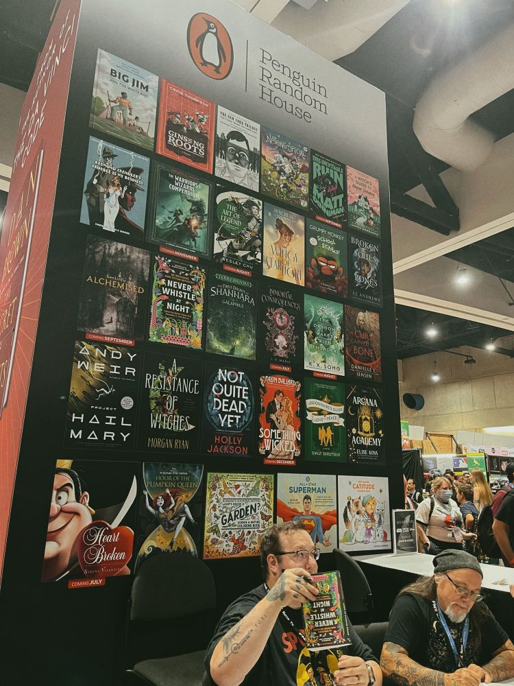 Photo of Shane Hawk & Theodore C. Van Alst Jr. signing copies of NEVER WHISTLE AT NIGHT at Penguin Random House’s booth during San Diego Comic-Con 2025. 