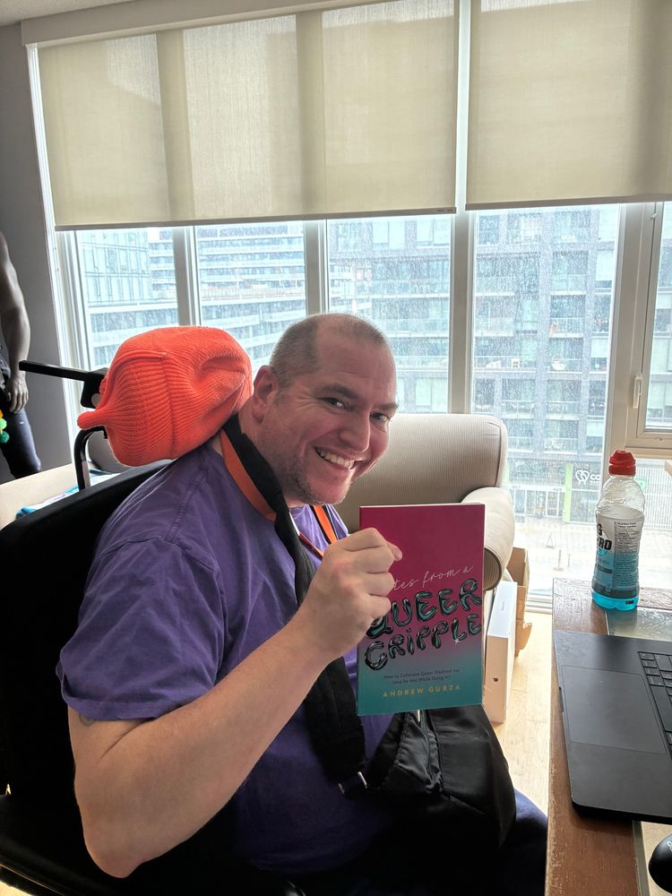 Andrew holding a copy of his book and smiling 
