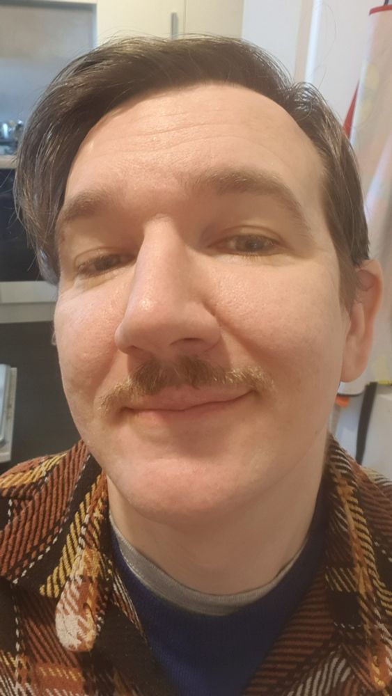 Selfie of a man with a short moustache and clean shaven otherwise.