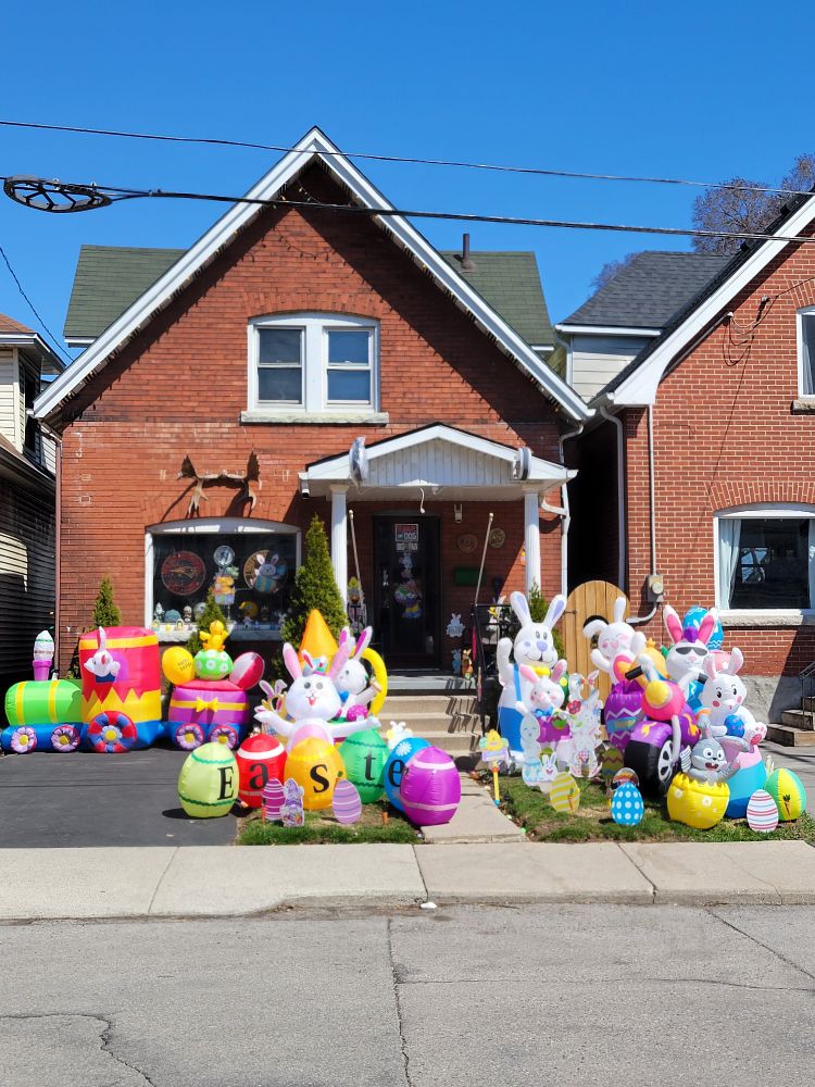 Brick house with a lawn display of colourful inflatable rabbits, train, and Easter eggs