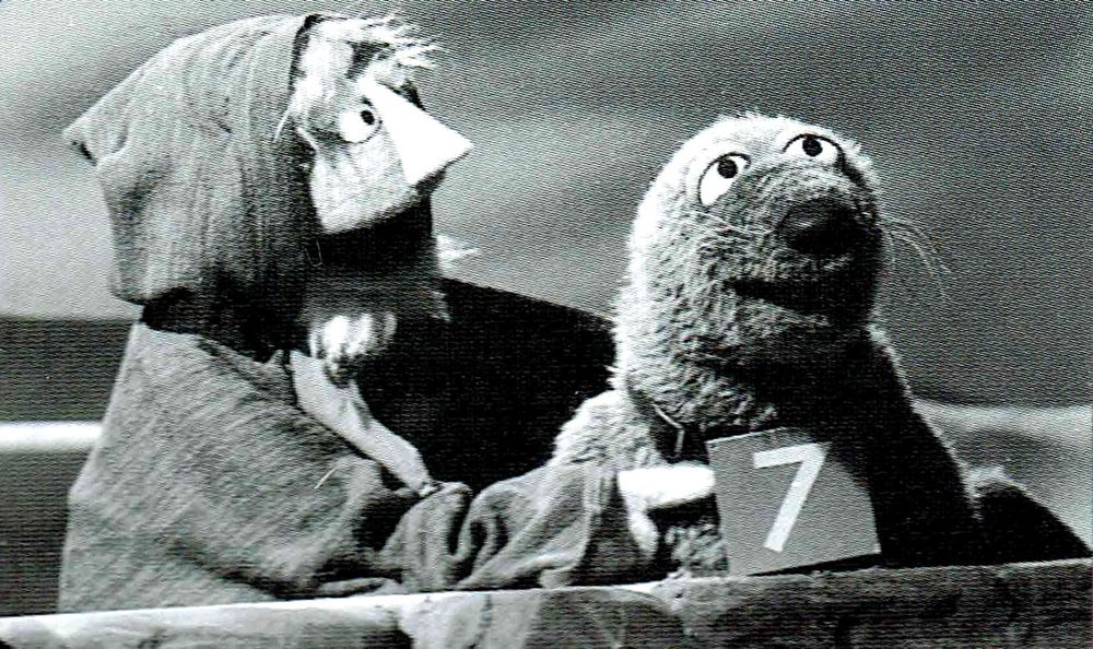Screengrab of a Muppet of a Swedish fisherman and a Muppet seal with the number 7 on a card around its neck. The Seventh Seal, in other words.