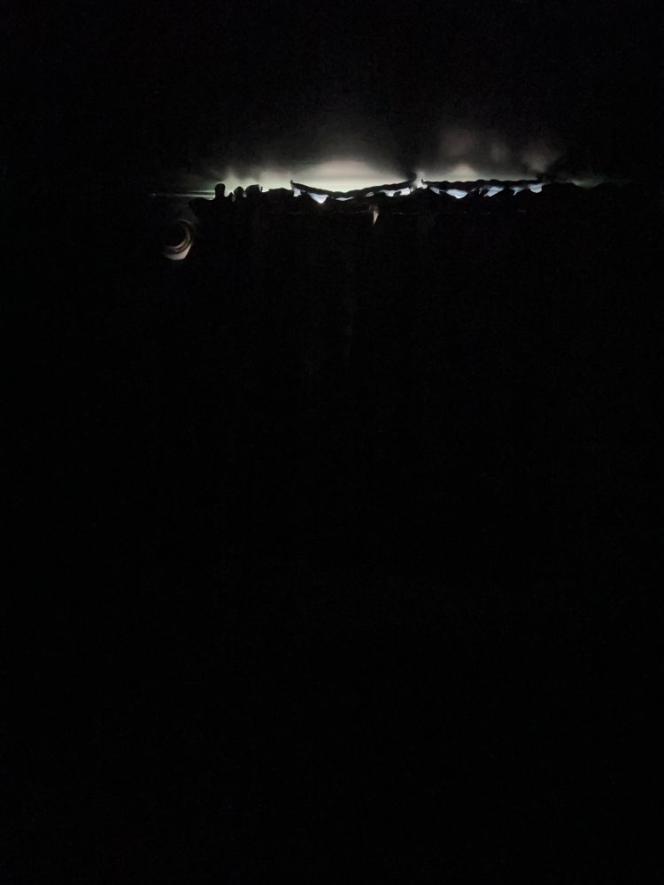Dark bedroom with some light slipping through at the top of the sun block curtains. The room is completely dark.