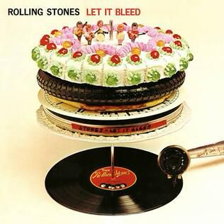 Album cover Rolling Stones Let it Bleed shows a stack of items above a turntable playing The Rolling Stones. Items in the stack waiting to play include a tape canister, clock, pizza, tire, and sugary decorated desert with tiny figures representing The Rolling Stones playing atop. 