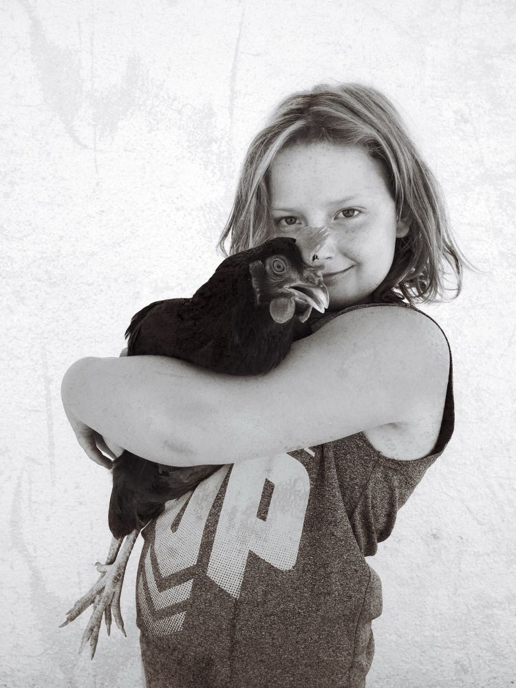 Black and white portrait of a young neighborhood girl with her pet chicken