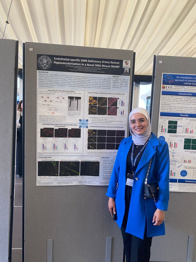 Labbie Alaa dressed extremely fashionably in blue, stood in front of fantastic science, her poster entitled 'Endothelial-specific SMN deficiency drives retinal vascularisation in a novel SMA mouse model.'