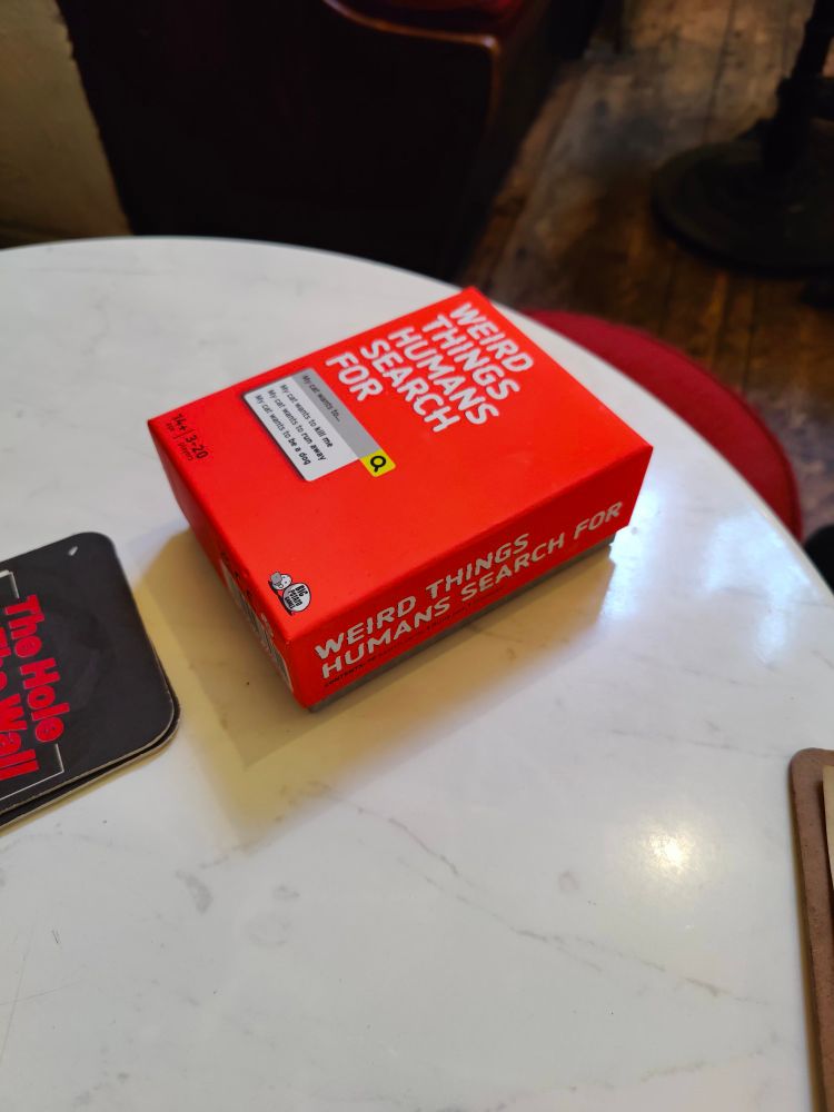A board game named "weird things humans search for" on a table
