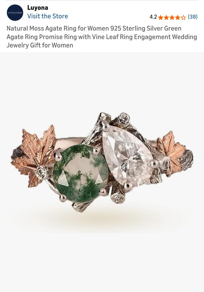 Picture of a ring that features tiny maple leaf designs and branches. There is a round stone that appears to be a moss agate and a pear shape stone beside it that has a clear color 