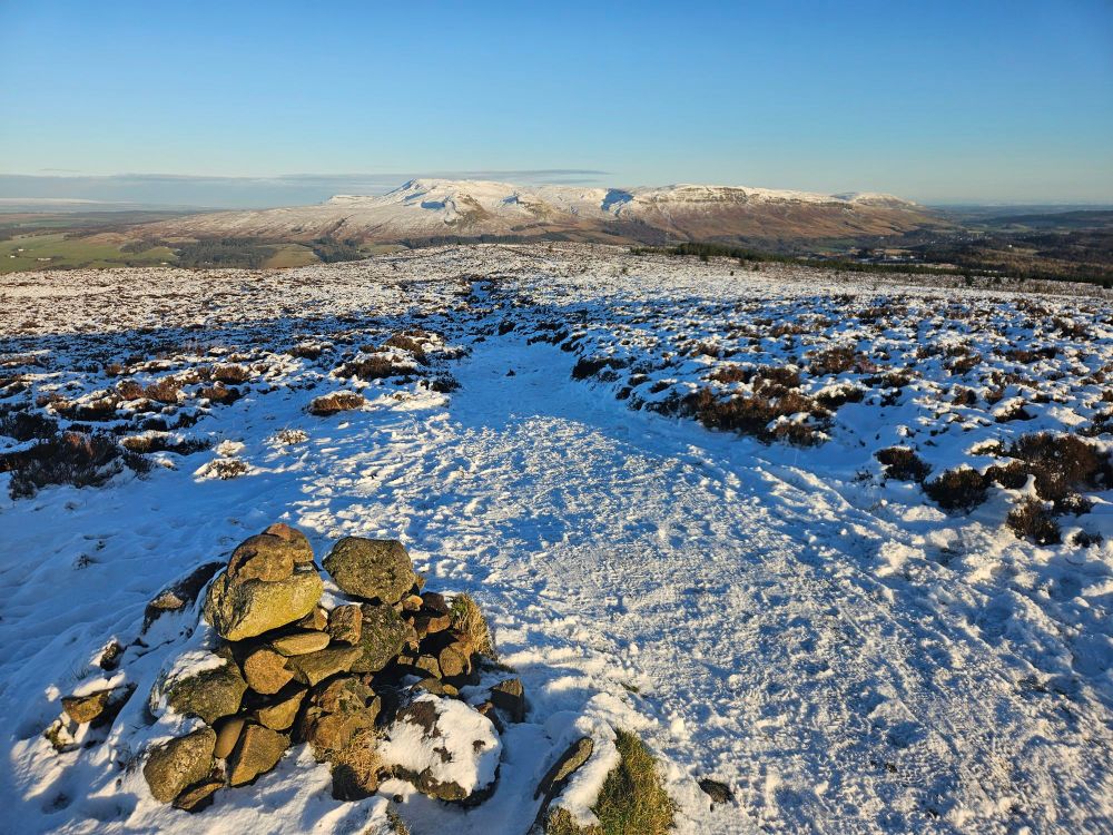 A cairn on a snowy hilltop, with views to the Campsie hills. 