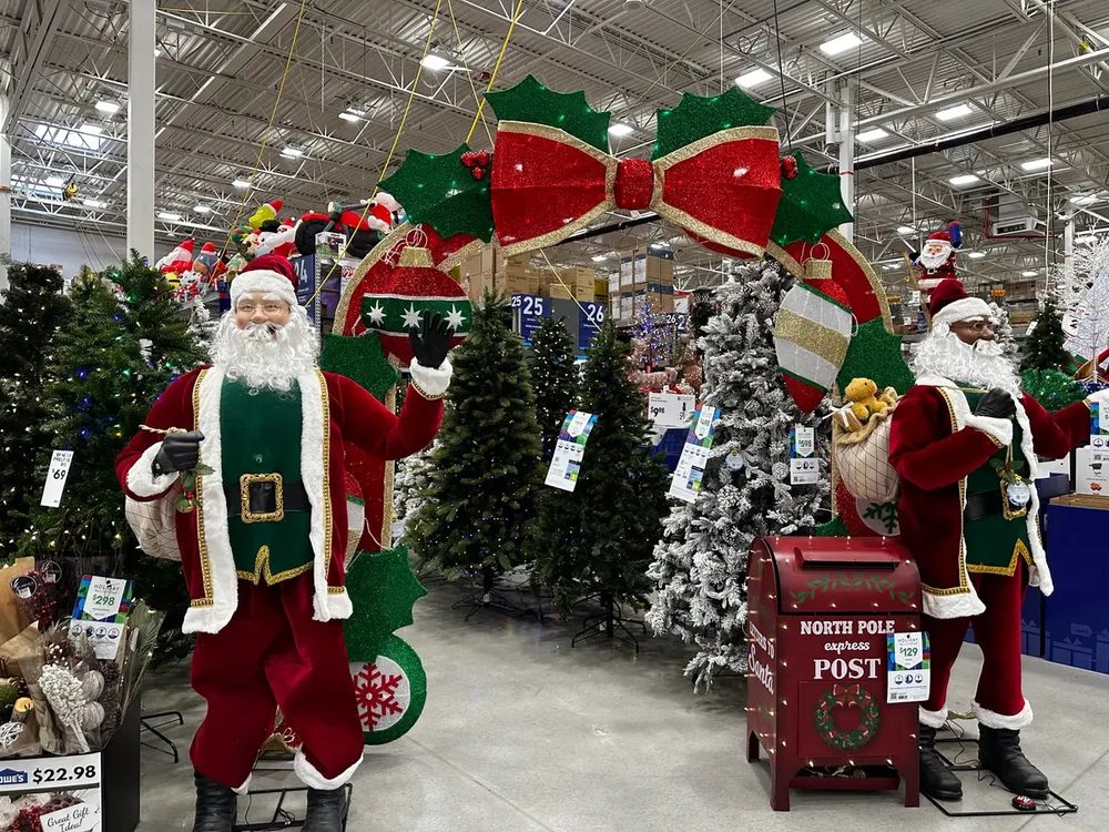 A Christmas display at Home Depot. Santa Claus, garish giant ribbons, trees with pre-installed lights, and a partridge in a pear tree.
