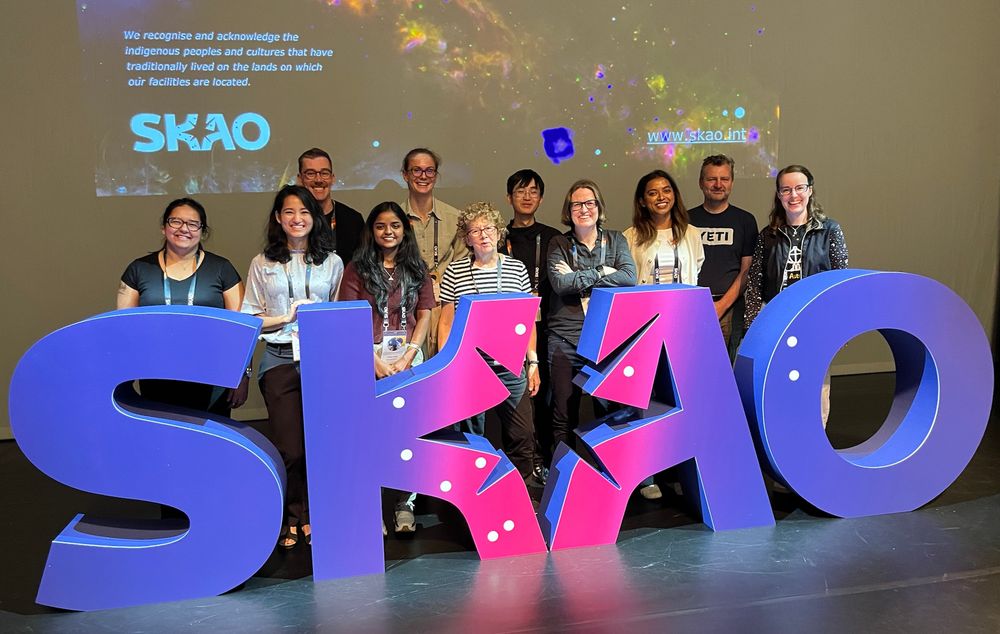 A picture of 11 people from our Sydney radio astronomy team behind giant letters that spell SKAO. The letters are blue/purple/bright pink.