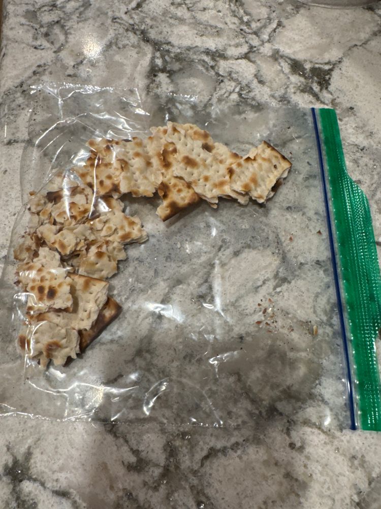 Varying sized matzoh in a sandwich ziplock bag on a stone counter 