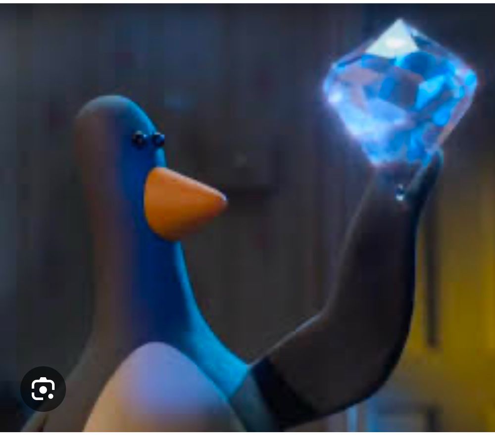 An image from Wallace and Gromit showing the character Feathers McGraw holding up a large blue multi-faceted diamond