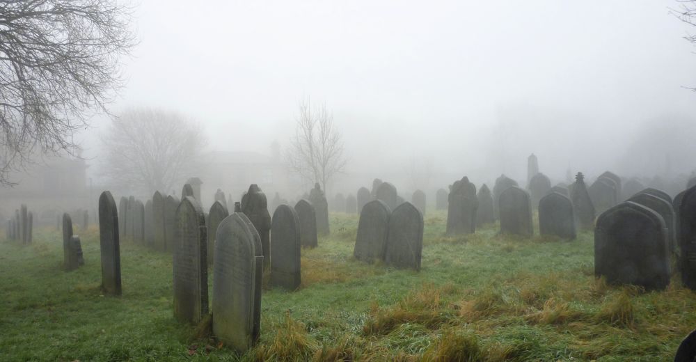 A moody image of Lister Lane Cemetery taken in December 2021 showing gravestones shrouded in fog.

