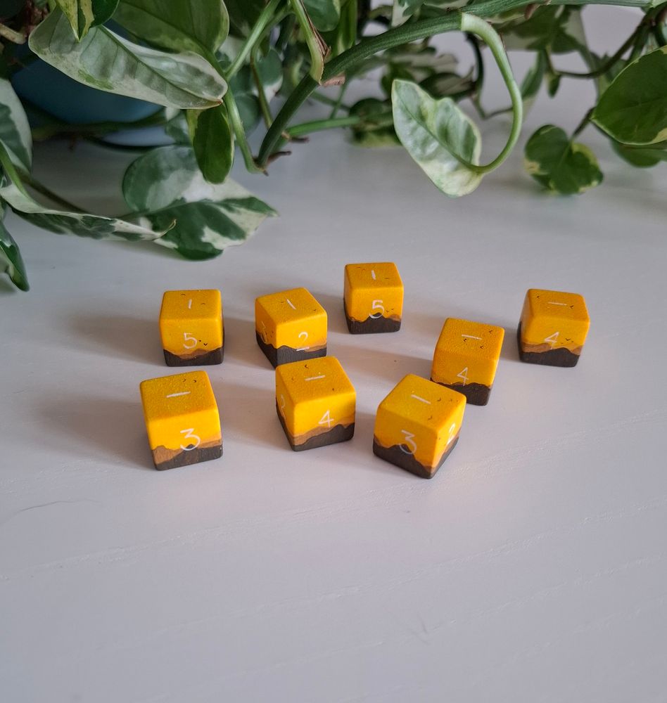 A picture of handpainted d6. They show a yellow sky with a mountain range in front
