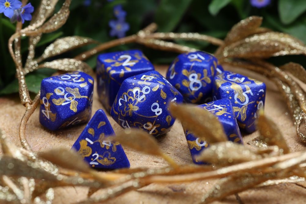 Handpainted dice with a blue base and gold florals painted ontop of it. The numbers are white