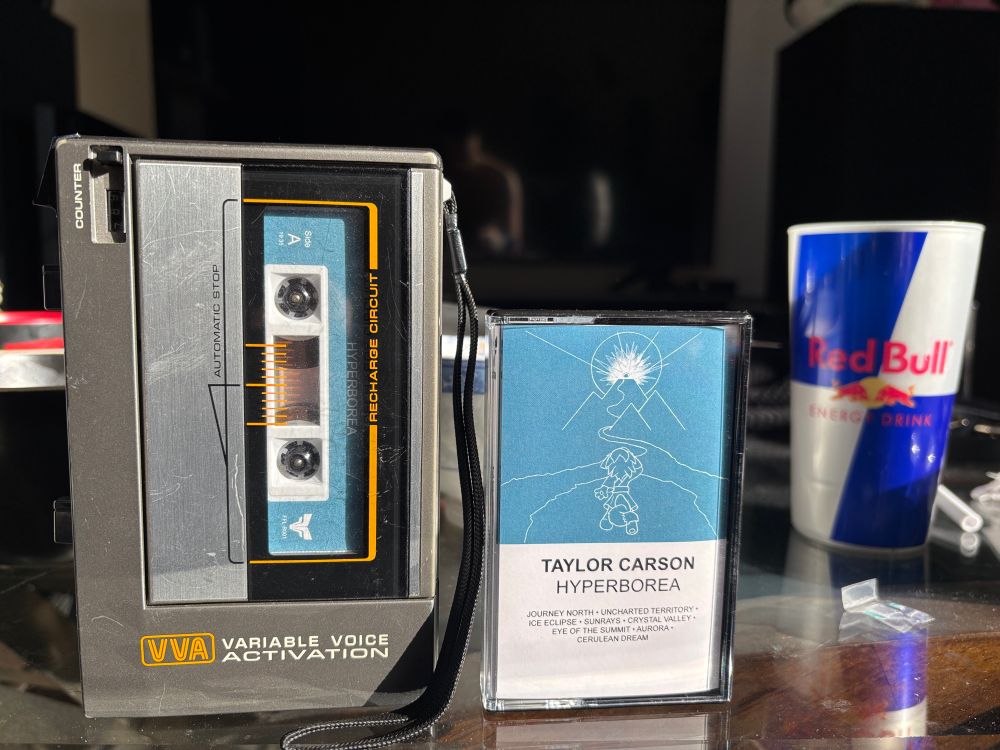 Cassette player with Taylor Carson’s Hyperborea playing. Out of focus Red Bull cup in the background 