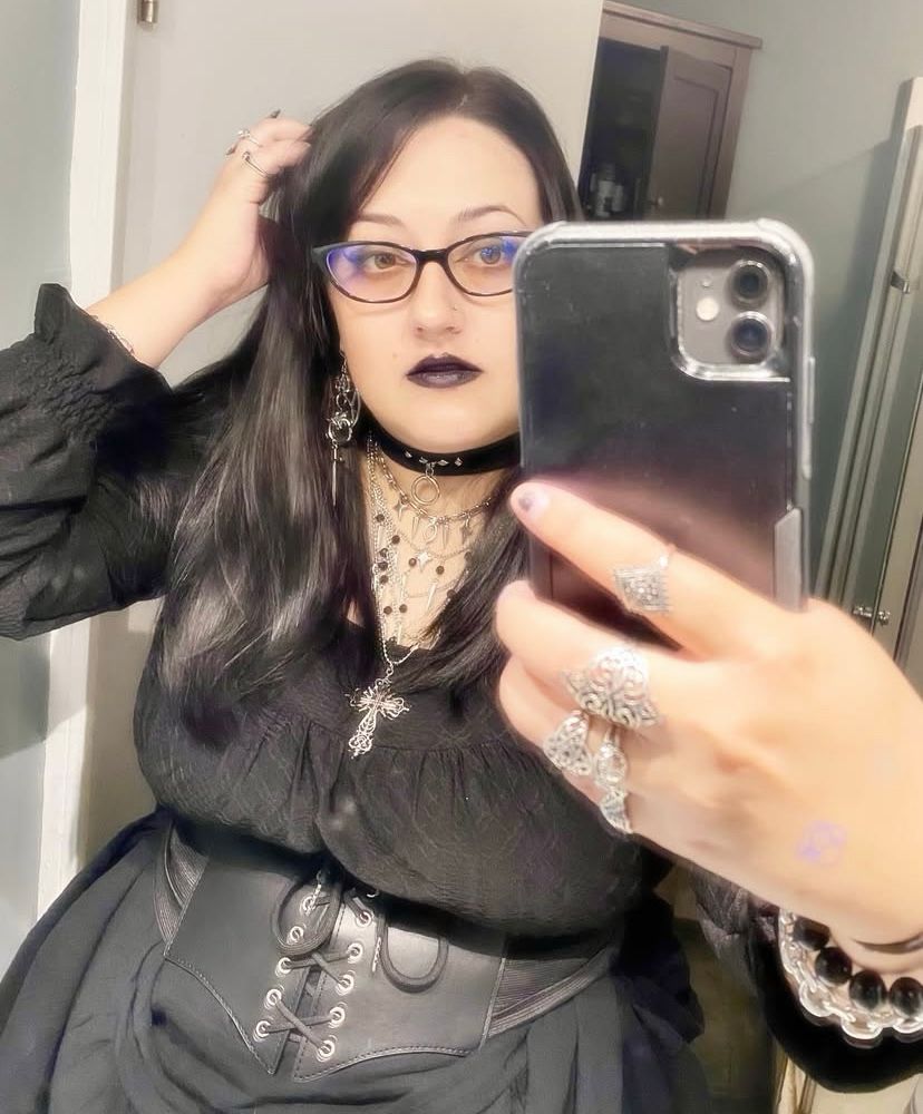 Pale white woman with glasses and black hairc dressed goth