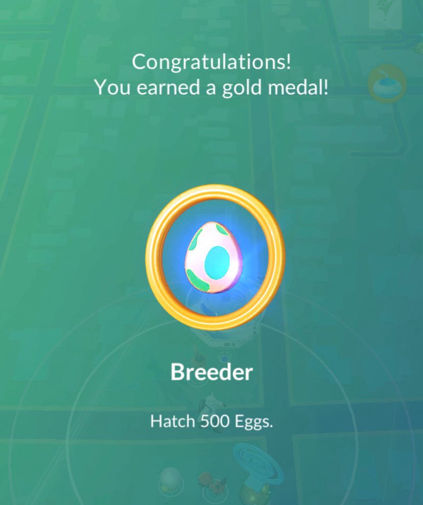 A screenshot of a medal reward in Pokemon GO for hatching 500 eggs. The title of the gold medal is Breeder