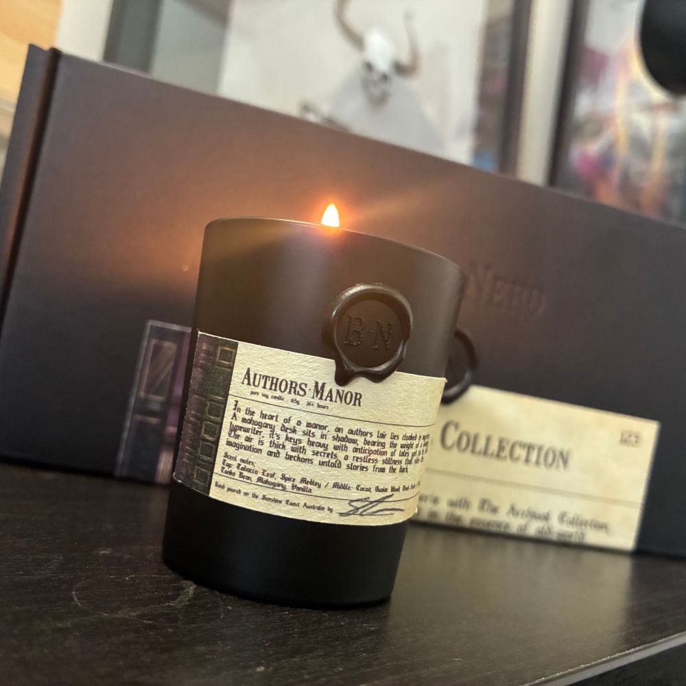 A lit candle in a black jar with a wax seal and parchment style label. Scent is Authors Manor. From Blanc+Nero