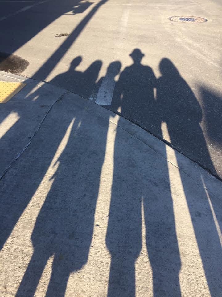 A family’s shadow is cast on a city street 