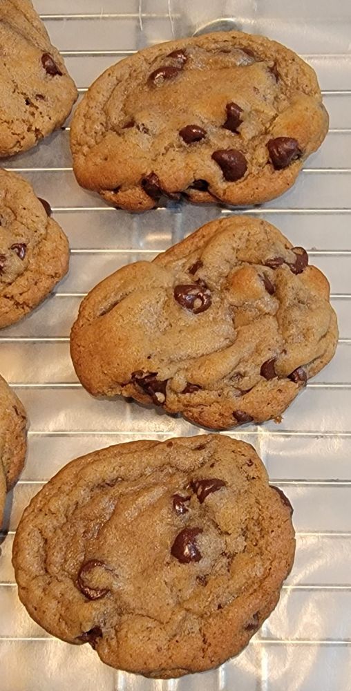 Freshly baked chocolate chip cookies cooling on wax paper. 